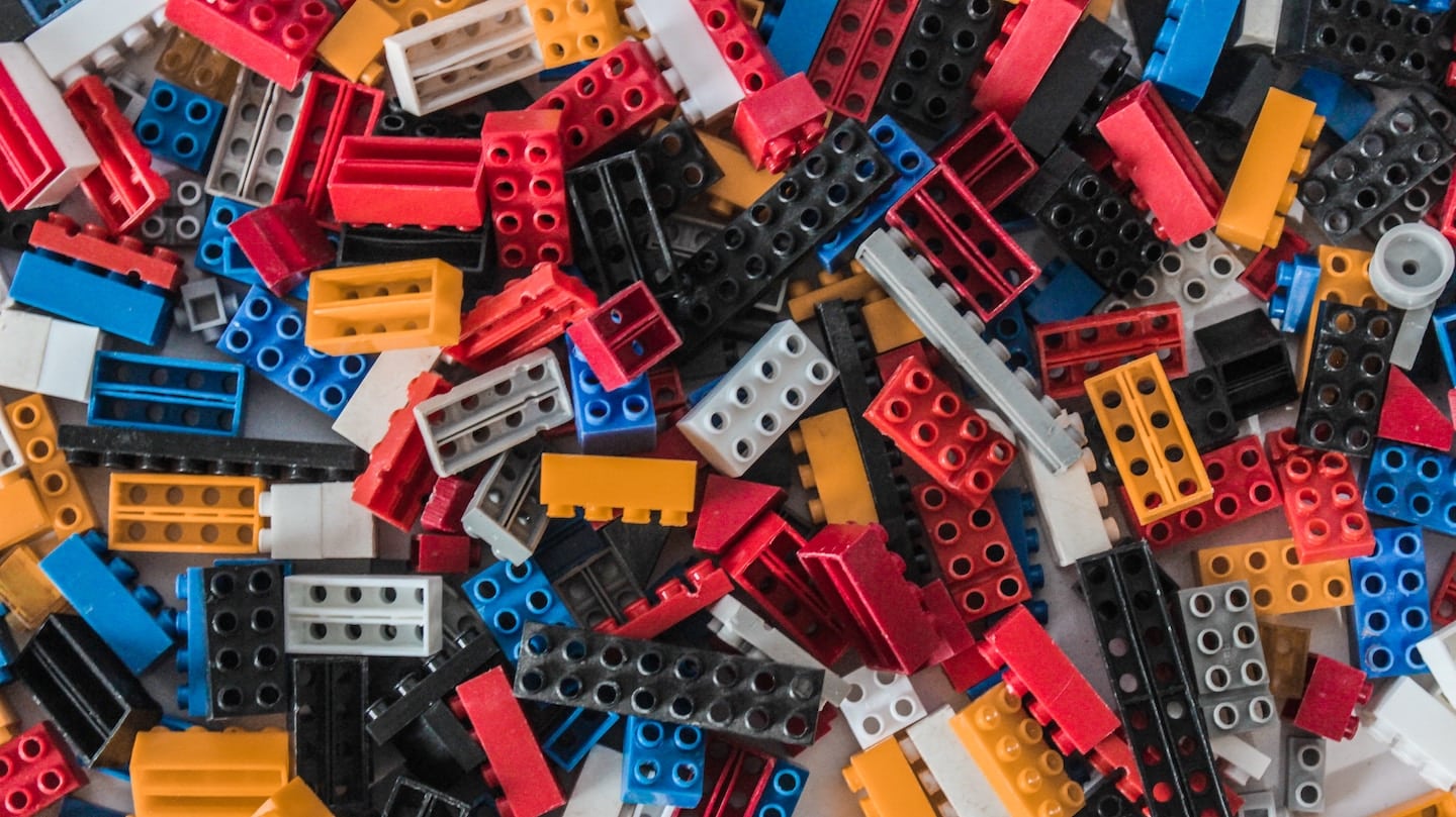 Briques de construction en plastique rouges, bleues, jaunes, noires et blanches en vrac