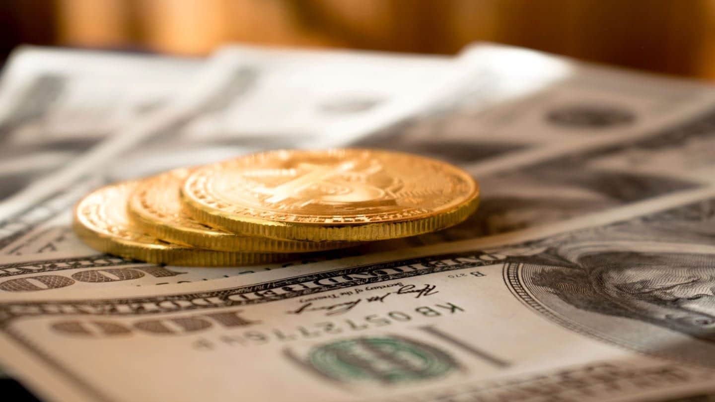 Pièces dorées posées sur des billets de 100 dollars