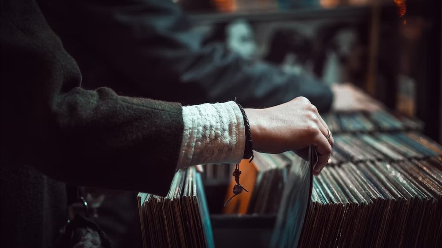 Main qui feuillette un bac de disques vinyles chez un disquaire